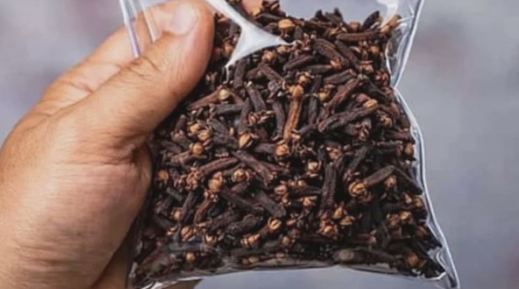 Una mano sosteniendo una bolsita de clavos enteros