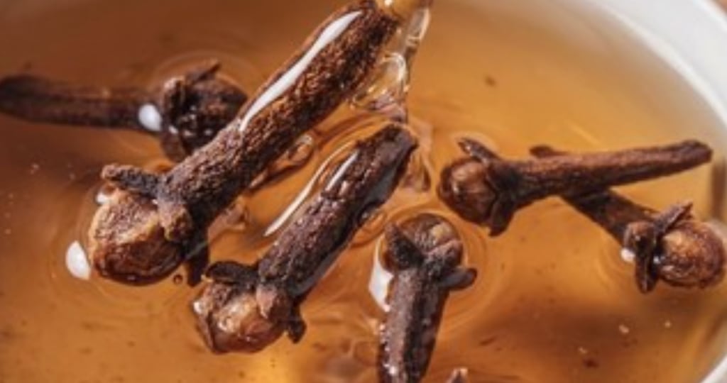 Botones de clavo en una infusión caliente, con vetas de aceite en la superficie